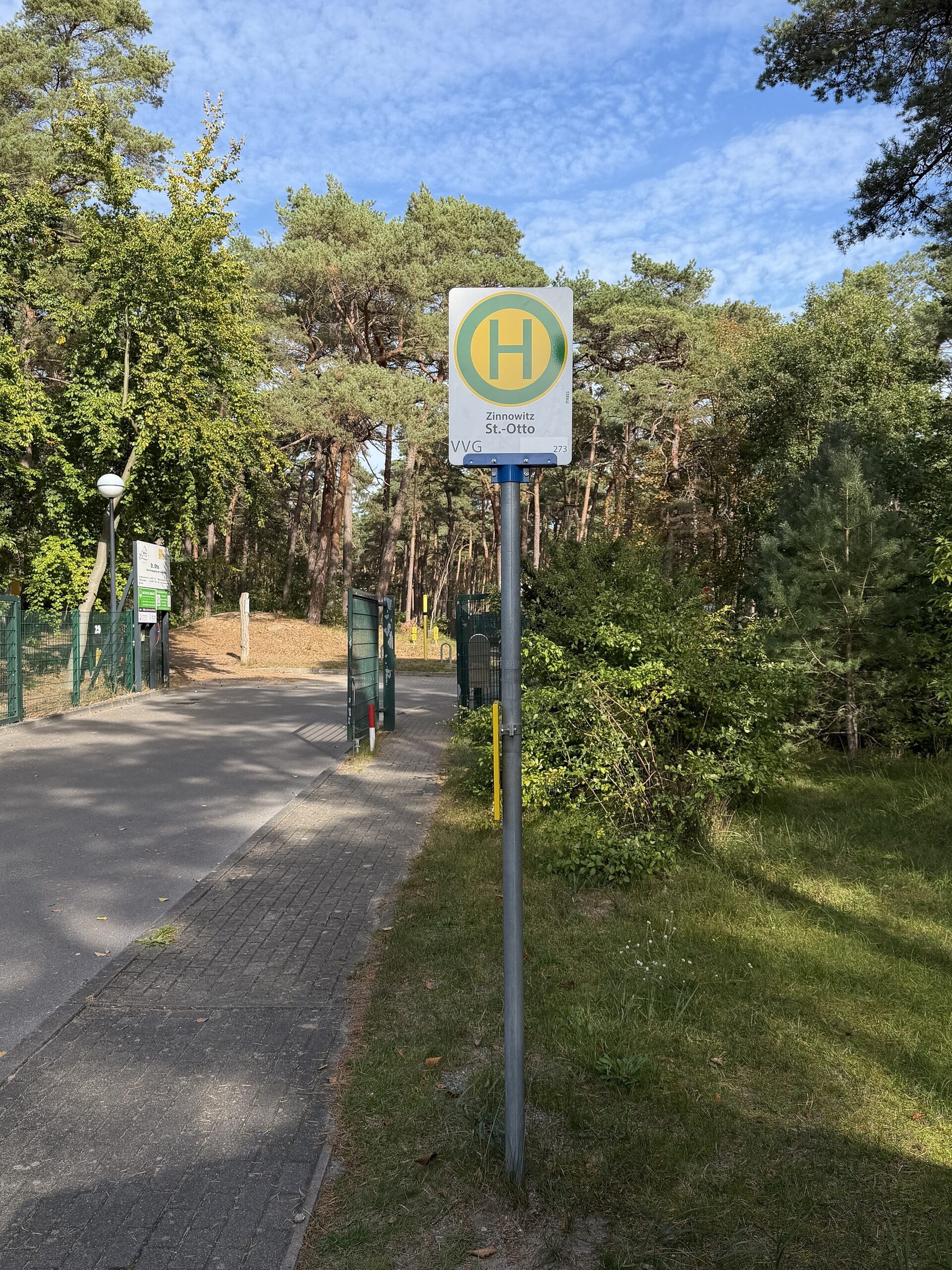 Bushaltestelle mit Haltestellenschild an einem Weg durch den Kiefernwald